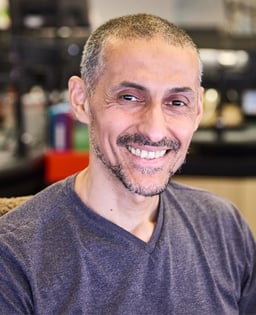 Personne en chandail gris dans un environnement intérieur flou.