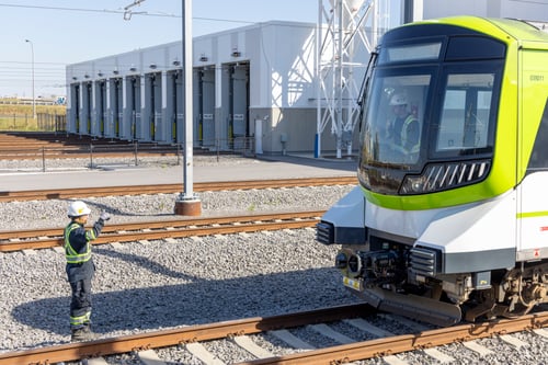 Train dans une cour ferroviaire avec deux employés