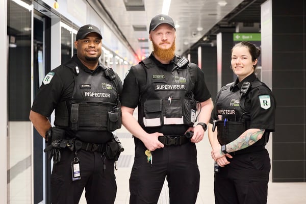 Trois agents de sécurité en uniforme dans une station, dont un superviseur.