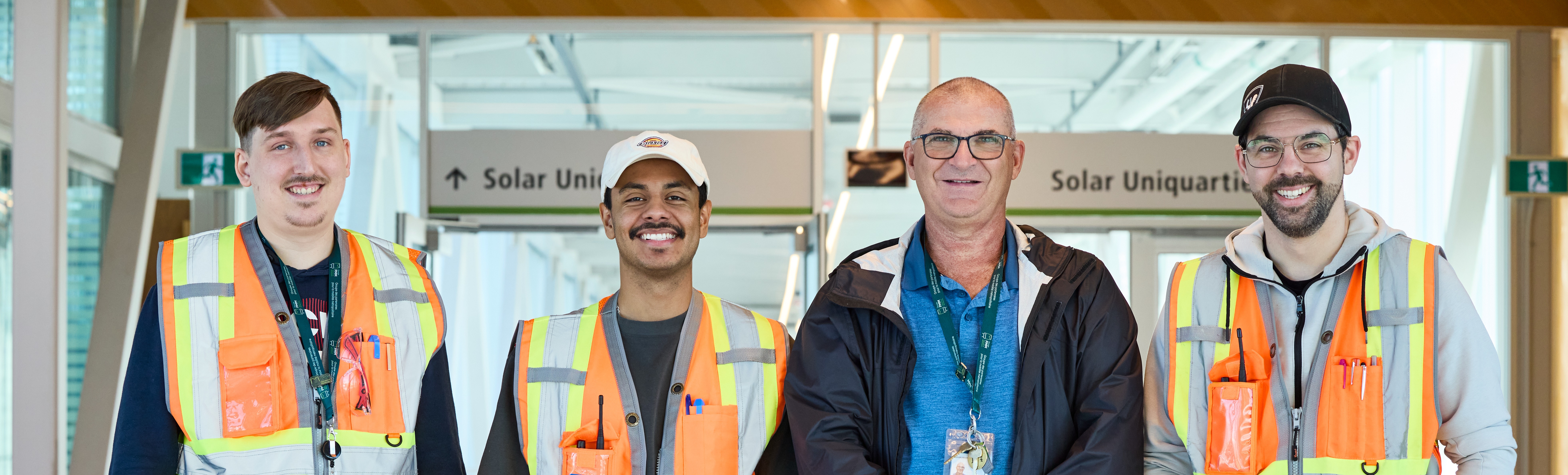 Quatre personnes en gilets de sécurité devant des panneaux "Solar Uniquartier".