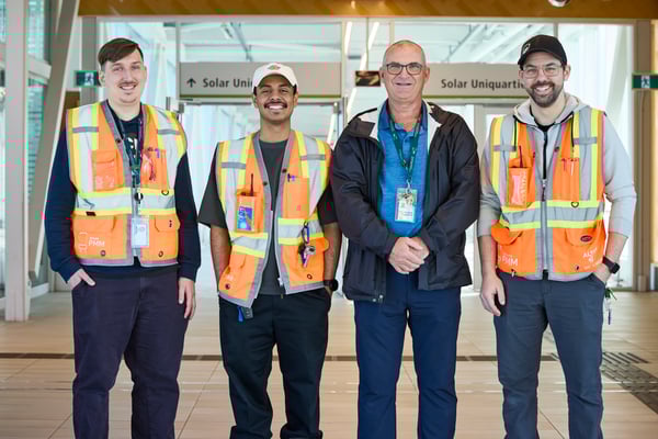 Quatre personnes en gilets de sécurité devant des panneaux "Solar Uniquartier".