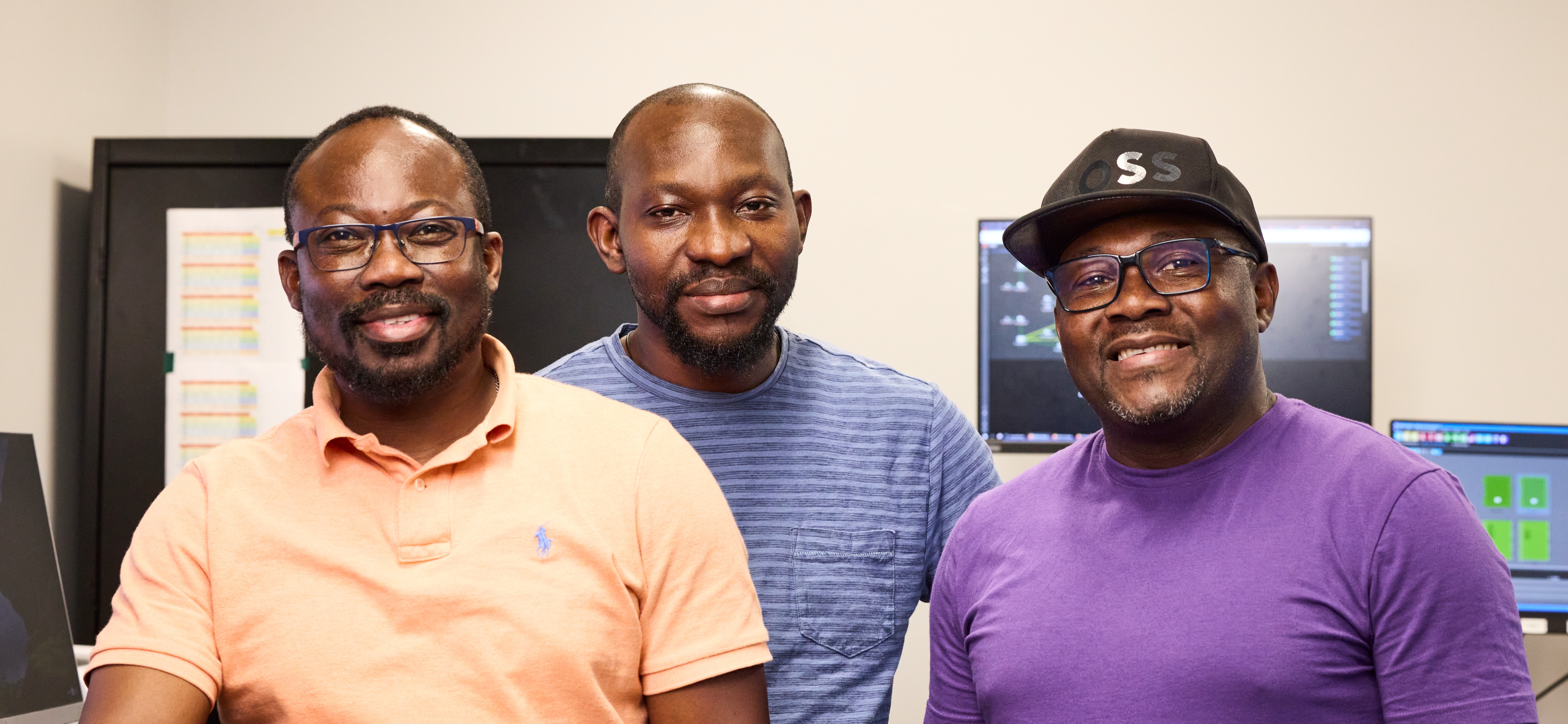 Trois personnes debout devant des écrans d’ordinateur