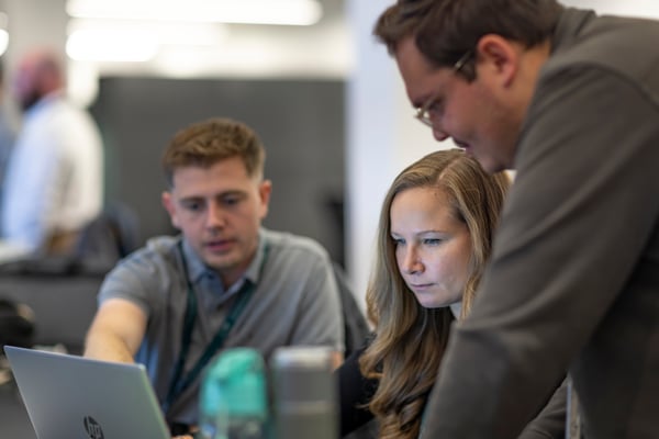 Trois personnes en réunion autour d’un ordinateur portable dans un bureau.