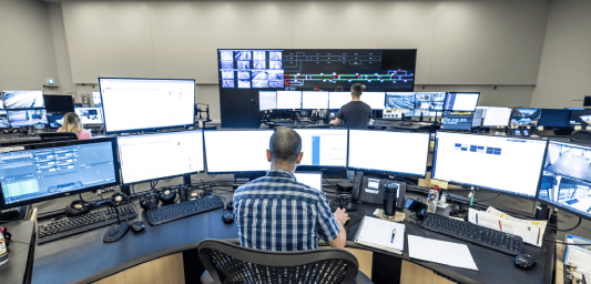 Homme derrière plusieurs écrans d'ordinateur