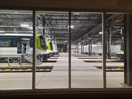 Intérieur d’un centre d’entretien ferroviaire avec plusieurs trains sur des voies parallèles.